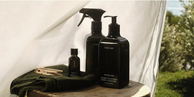 Best all-natural laundry detergent from Homecourt displayed with linen spray and fragrance oil outdoors.
