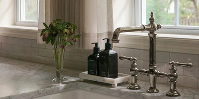 Bright kitchen sink with non-toxic dish soap bottle on a marble counter by a window.