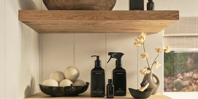 Concentrated laundry detergent displayed with linen spray and fragrance oil beside wool dryer balls and minimalist decor