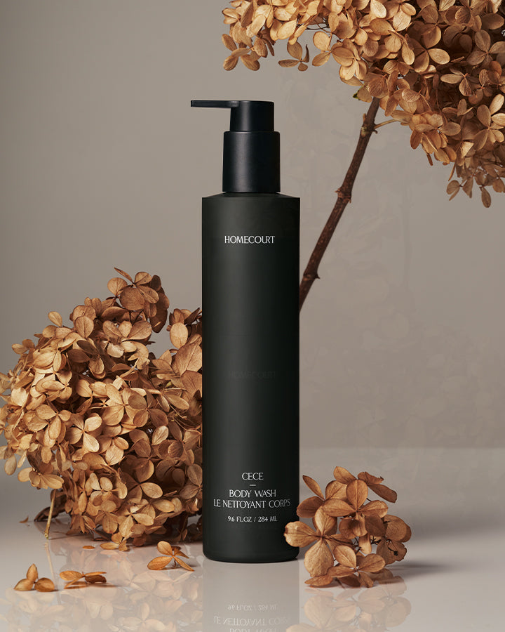 Front view of CECE body wash bottle with matte black pump and dried hydrangea on neutral background
