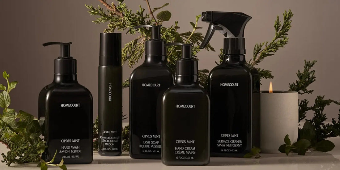 Front view of Homecourt Cipres Mint cleaning bottles showing dish soap and surface cleaner in black bottles with greenery backdrop
