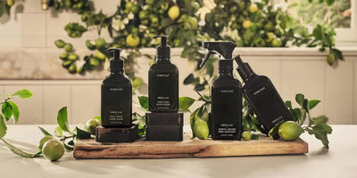 Front view of Homecourt Neroli Leaf cleaning bottles, black pump and spray, on a wood board with citrus and leaves