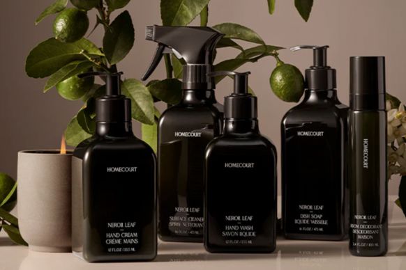 Front view of Homecourt Neroli Leaf cleaning bottles (spray, pump, hand wash) on a neutral surface with citrus branches and a lit candle