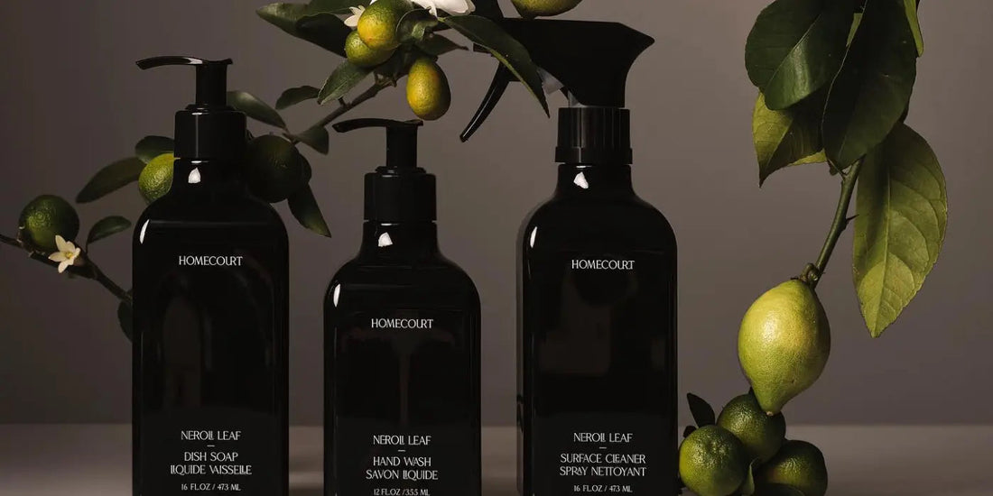 Front view of three Homecourt Neroli Leaf bottles (hand wash, dish soap, surface cleaner) with citrus branch backdrop