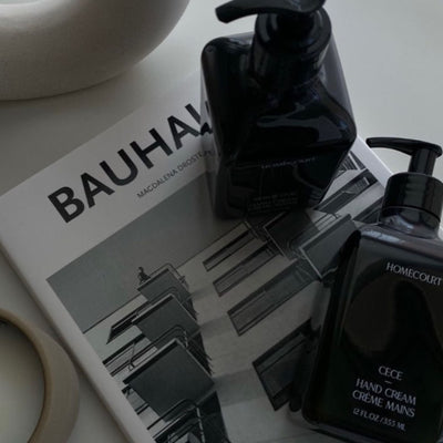 Top-down view of two CECE hand cream pump bottles showing pump dispensers on a Bauhaus book