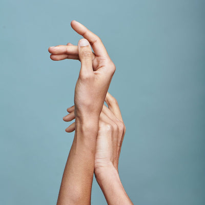 Close-up of two hands gently touching against a pale blue background