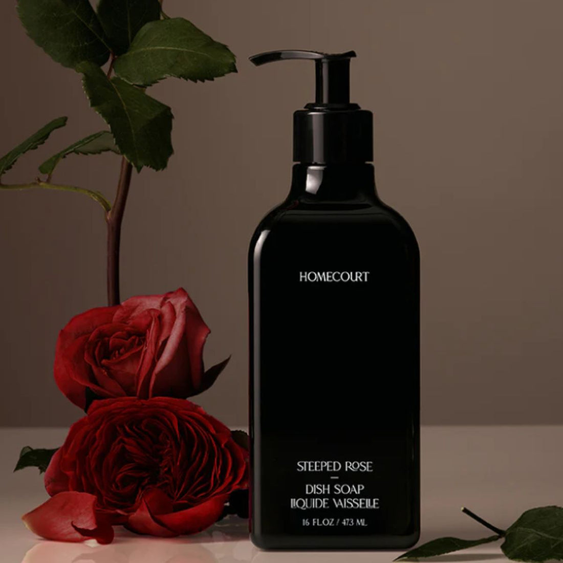 Front view of Homecourt Steeped Rose dish soap bottle with black pump, label reading Steeped Rose Dish Soap 16 fl oz, and red roses on a brown background