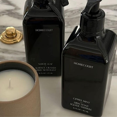Front view of Homecourt Cipres Mint dish soap pump, black rectangular 16 fl oz bottle with white text on marble countertop and candle