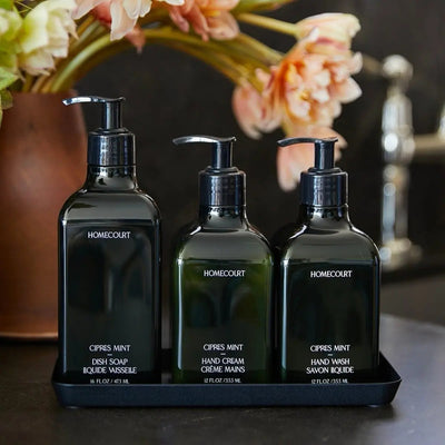 Three Homecourt Cipres Mint pump bottles (dish soap 16oz, hand cream 12oz, hand wash 12oz) on a black tray with pink flowers