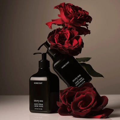 Front view of Homecourt Steeped Rose hand wash and hand cream in black pump bottles with deep red roses on a neutral backdrop
