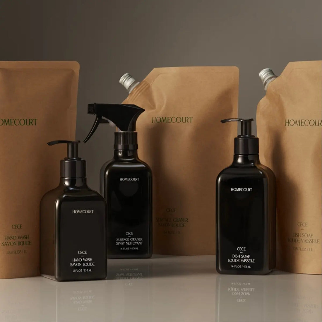 Front view of black Homecourt CECE hand wash, dish soap, and surface cleaner bottles showcasing pumps and spray nozzle with kraft refill pouches in the background