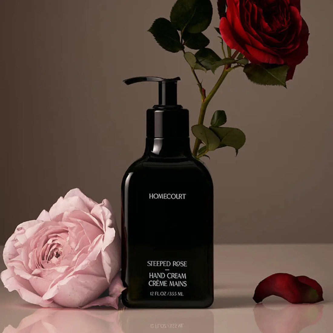 Front view of Homecourt Steeped Rose hand cream 12 fl oz showing black bottle with white text and roses on a neutral background