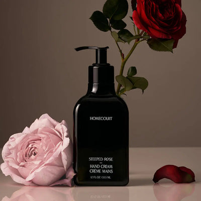 Front view of Homecourt Steeped Rose hand cream 12 fl oz showing black bottle with white text and roses on a neutral background