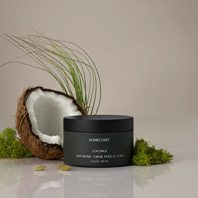 Front view of Homecourt Cocomoi body butter (6.7 fl oz / 200 ml) in matte black jar with split coconut and moss backdrop