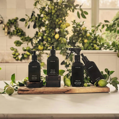 Homecourt cleaning bottles arranged on a wooden board with limes and green leaves in a sunlit kitchen