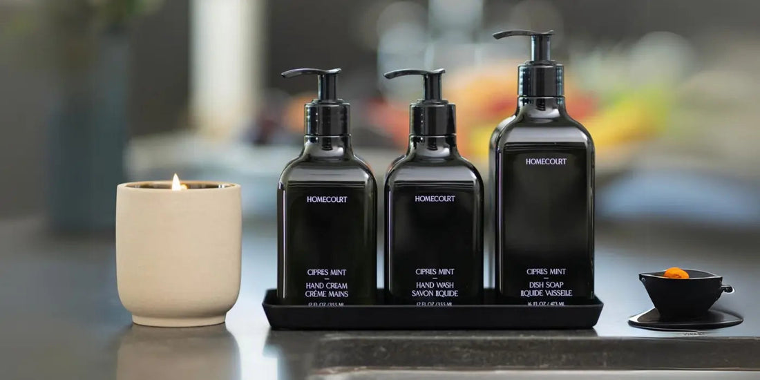 Front view of Homecourt Cipres Mint dish soap with matching hand wash and hand cream, black pump bottles on a tray on a kitchen counter