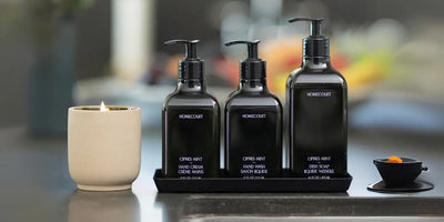 Front view of Homecourt Cipres Mint dish soap with matching hand wash and hand cream, black pump bottles on a tray on a kitchen counter
