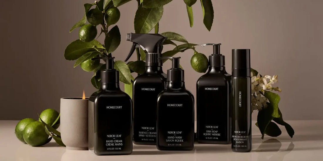 Front view of Homecourt Neroli Leaf cleaning collection in black pump and spray bottles with limes and blossoms