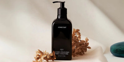 Front view of Homecourt black Laundry Concentrate pump bottle showcasing label text with dried florals on a neutral backdrop