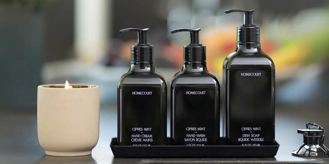 Homecourt Cipres Mint hand cream, hand wash, and dish soap in a black tray beside a lit candle