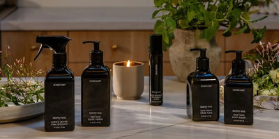 Front view of Homecourt Steeped Rose cleaning collection with black pump and spray bottles on a marble countertop