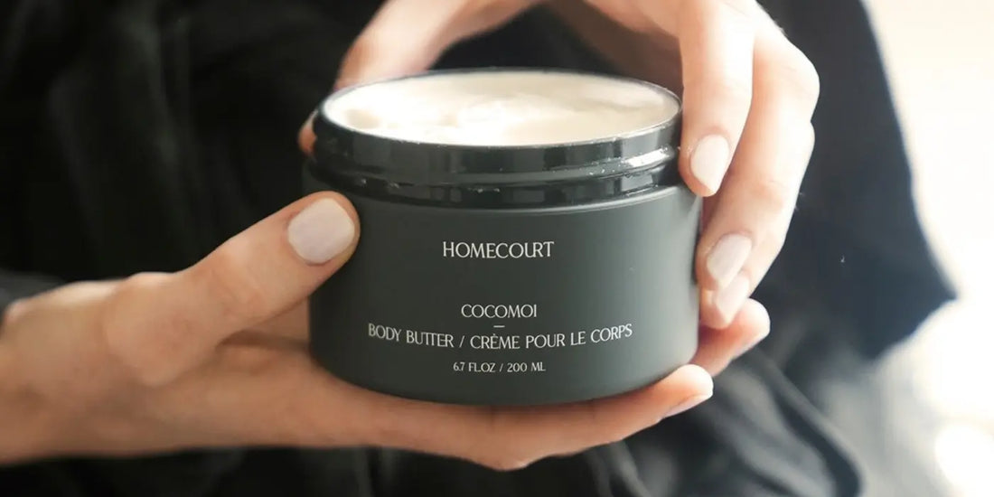Body balm coconut butter in dark jar held in hands with creamy texture visible