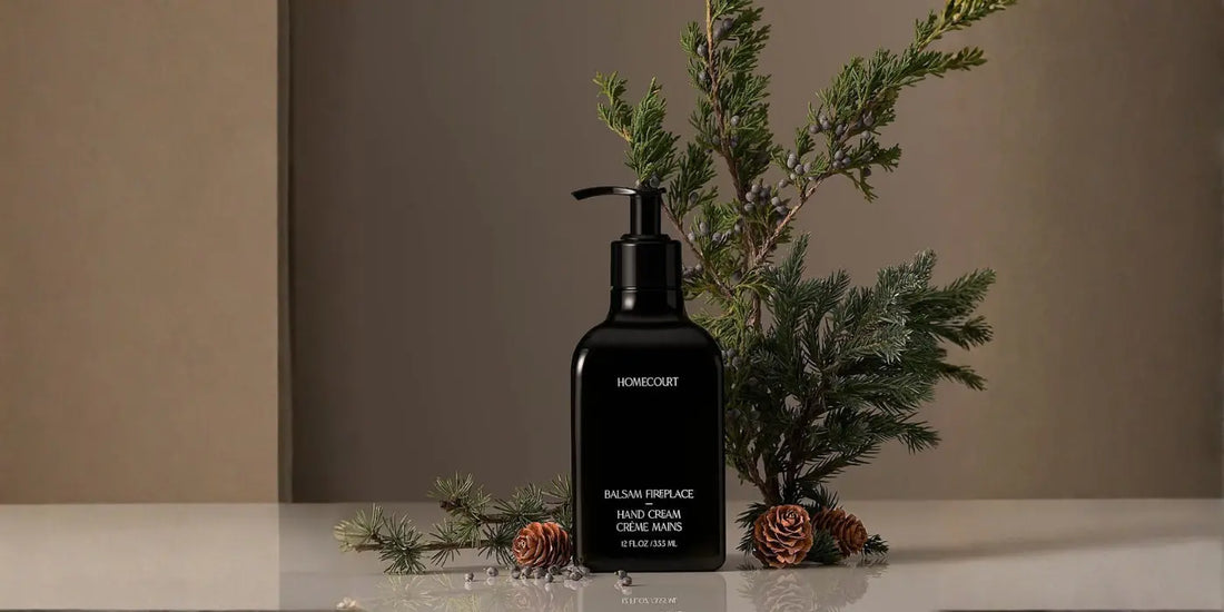 Premium hand cream balsam fireplace formula in dark dispenser with dried pinecones and evergreen branches