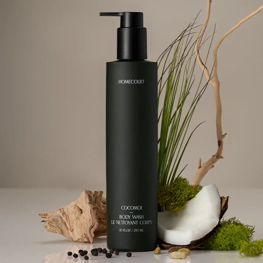 Organic body wash bottle with natural ingredients like coconut, moss, and driftwood arranged around it