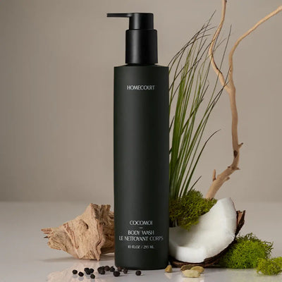 Organic body wash bottle with natural ingredients like coconut, moss, and driftwood arranged around it