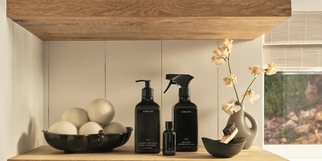 How to reduce toxins in your home with stylish black bottles of natural laundry and linen care products on wooden shelves.