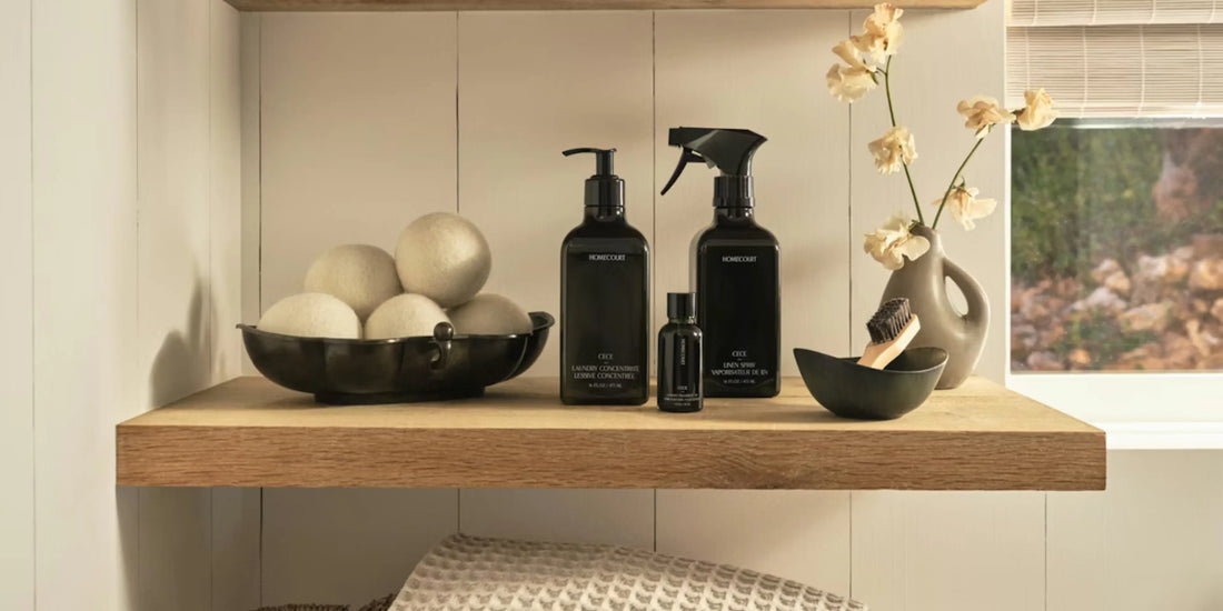 Homecourt laundry collection showcased on wooden shelf with linen spray, detergent, dryer balls, and decorative accents.