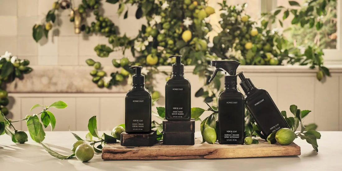 Full set of Homecourt Neroil Leaf kitchen cleaning products arranged on a wood board with fresh citrus branches and lemon fruit.