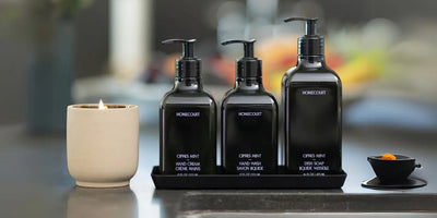 Plant-based dish detergent displayed with matching hand wash and hand cream in a modern kitchen beside a lit candle