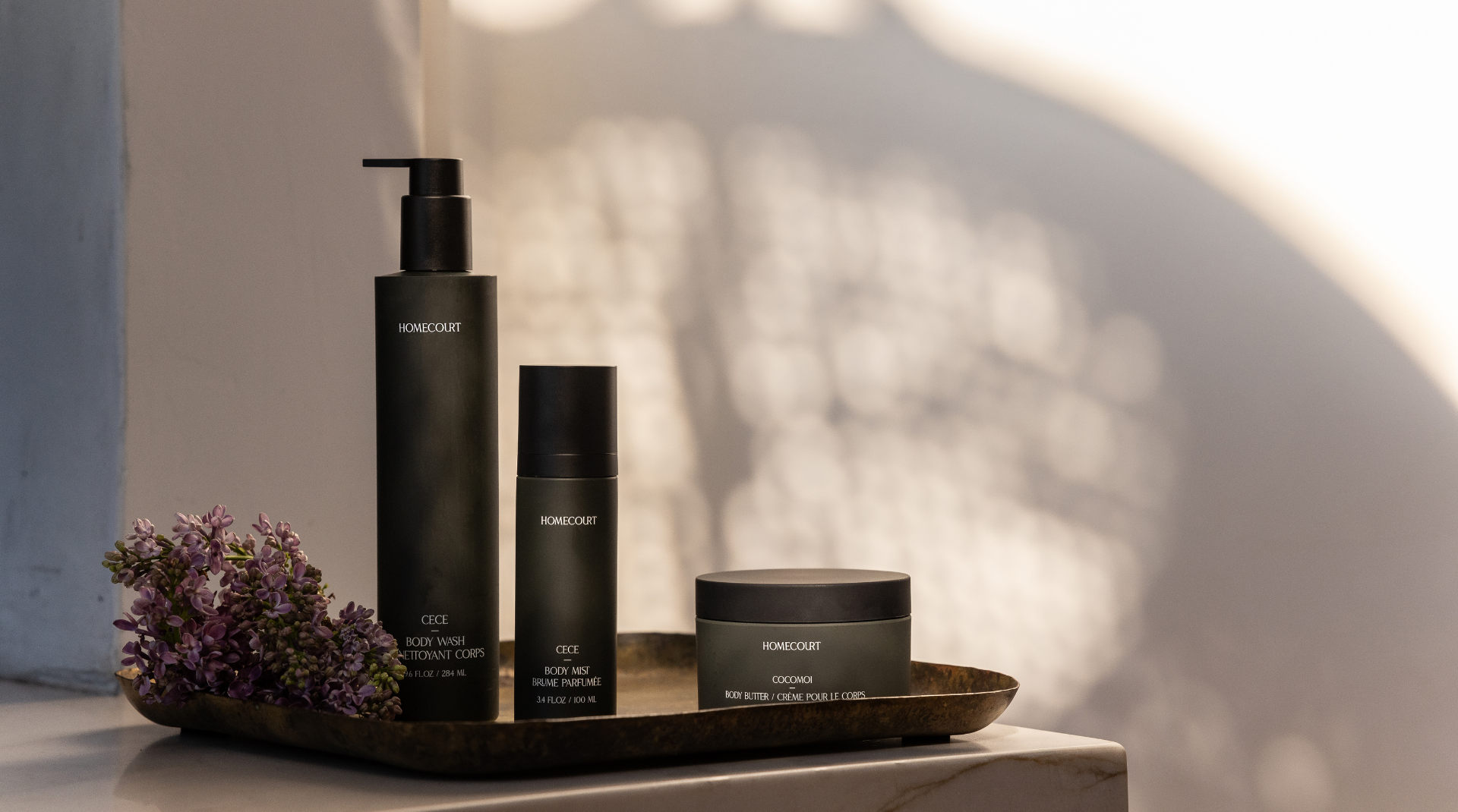 Set of black skincare products on a wooden tray with a blurred background