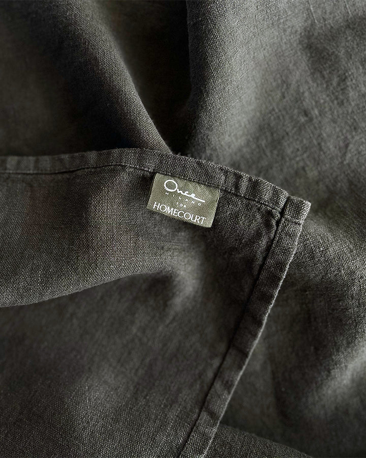 Black linen robe close-up showing Homecourt label on textured fabric.