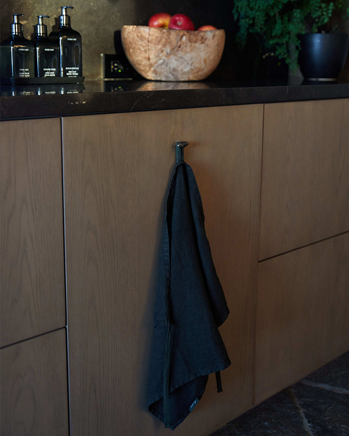 Luxury linen robe hanging from a hook on a wooden cabinet in a modern kitchen.