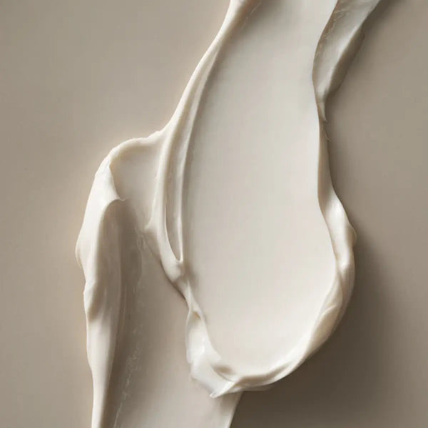 Coconut body butter texture swirled on a neutral background, highlighting its creamy and hydrating consistency.