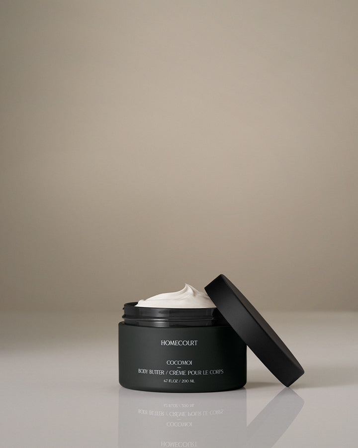 Coconut body butter in an open dark green jar labeled Cocomoi by Homecourt.