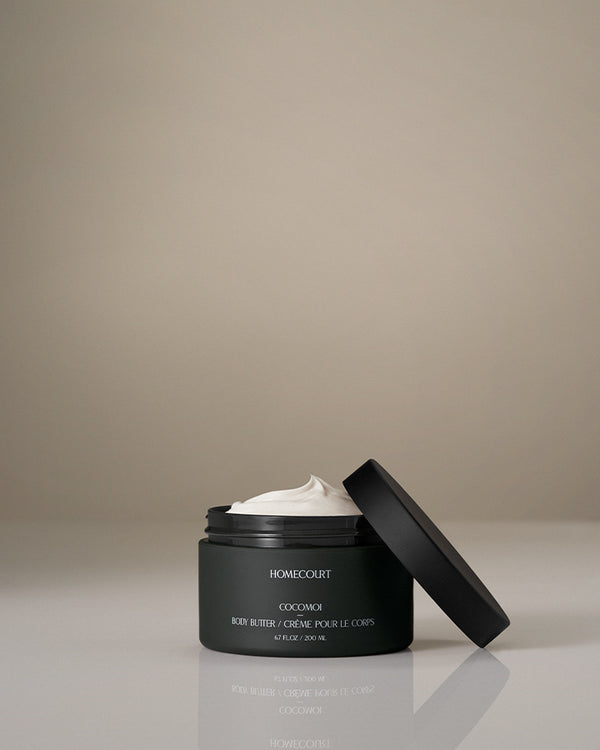 Coconut body butter in an open dark green jar labeled Cocomoi by Homecourt.
