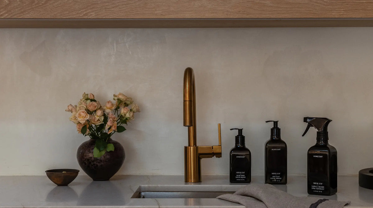 Homecare products beside a kitchen sink, including Neroli Leaf hand wash, dish soap, and space cleaner