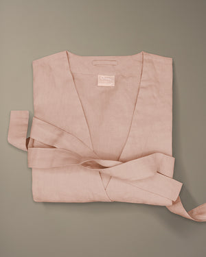 Once Milano x Homecourt linen robe in blush pink folded with belt on a beige background