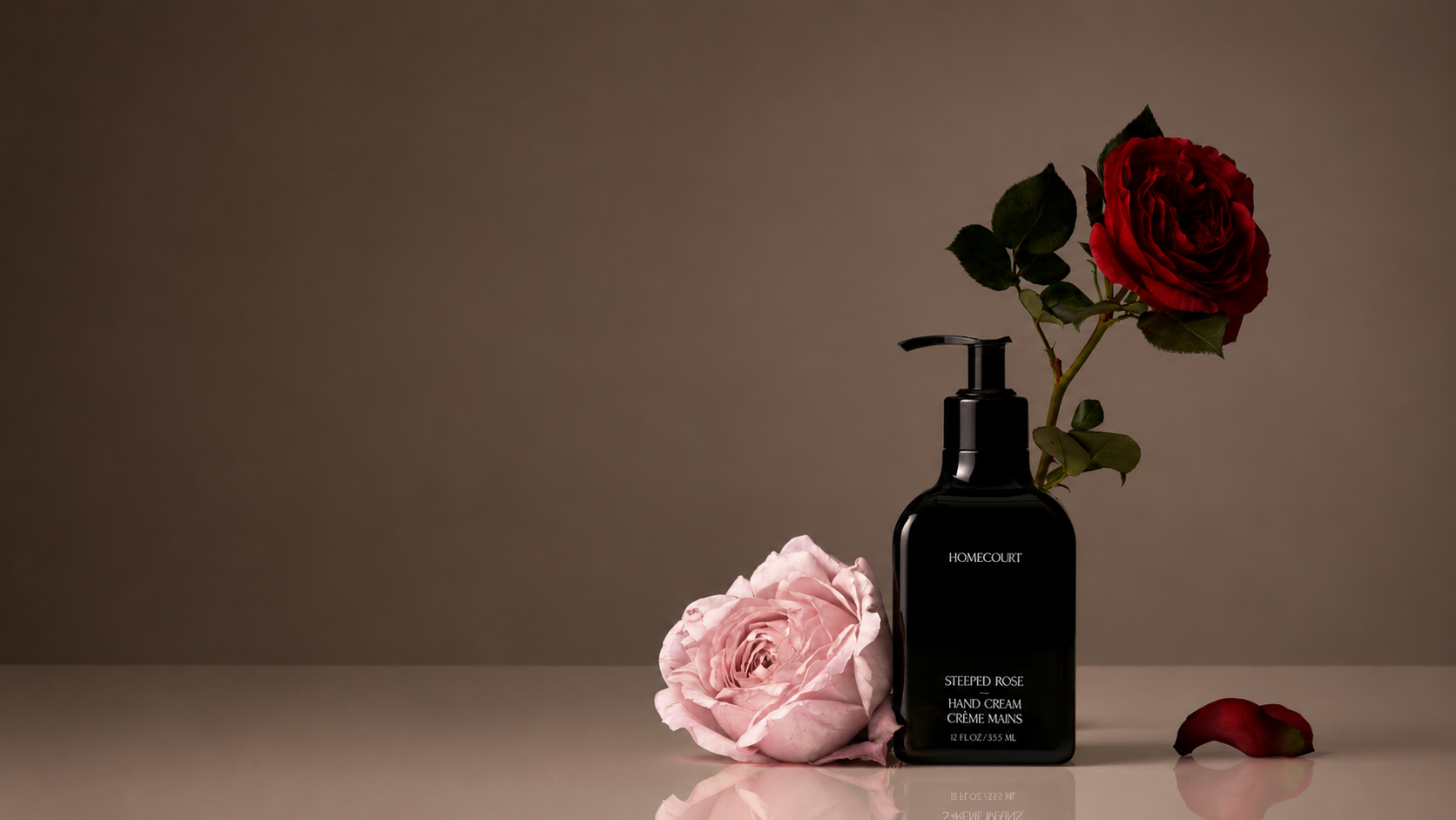 Black bottle with pink and red roses on a neutral background.